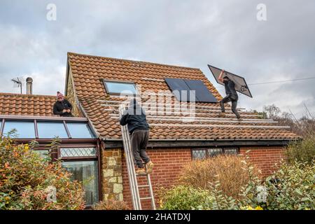 Workers installing solar panels or pv cells on the pantiled roof of a Norfolk cottage.  NB: The premises in the photograph are Property Released. Stock Photo