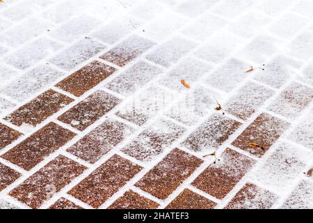 The texture of the cobblestone path covered with the first snow in winter. Abstract winter background. Stock Photo
