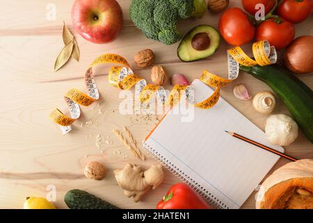 Vegetables on a wooden table and open notepad with empty leaf and pencil to score. Top view. Horizontal composition. Stock Photo