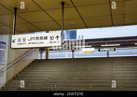 Stairway to platform in the Kyoto railway station with white information board hanging from ceiling. No people. Stock Photo