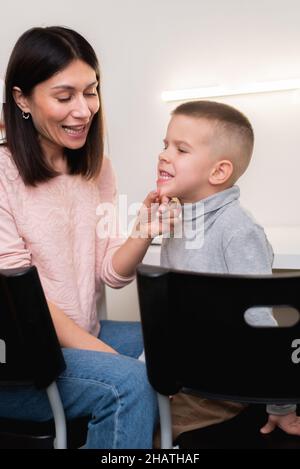 A beautiful woman speech therapist deals with the boy and teaches him the correct pronunciation and competent speech. Stock Photo