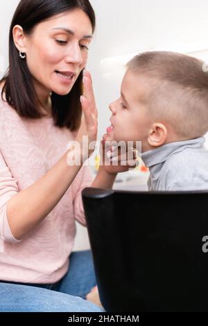 A beautiful woman speech therapist deals with the boy and teaches him the correct pronunciation and competent speech. Stock Photo