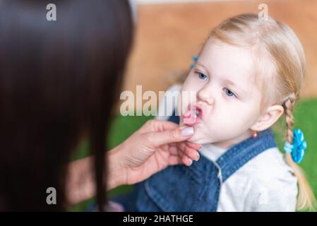 Woman speech therapist helps little girl to correct her speech in her office Stock Photo