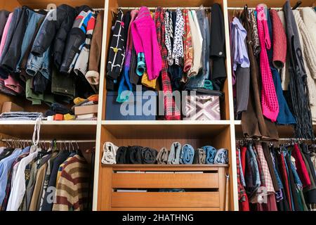 Collection of multicolored assorted clothes placed accurately on rails and hangers with shelves in walk in closet Stock Photo