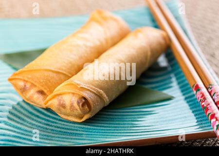 From above of delicious spring rolls served on blue ceramic plate with chopsticks on light table Stock Photo