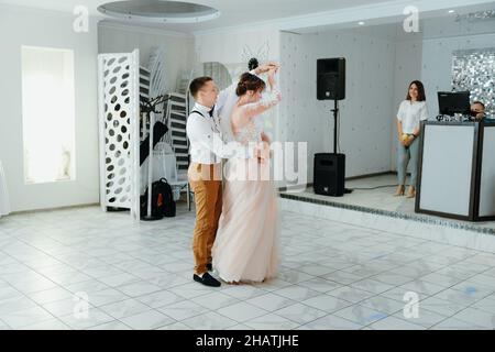 beautiful caucasian couple just married and dancing their first dance. Just married couple dancing in front of their unrecognizable friends. Stock Photo