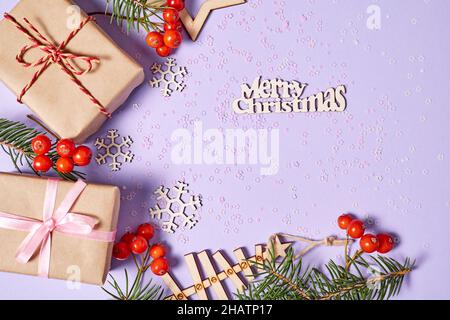 Christmas gift boxes and New Tear tree with fir branches and rowan berries on purple paper background with snowflakes and sparkles Stock Photo