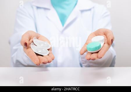 choosing between types of contact lenses. Doctor Ophthalmologist holding in hands one-day soft contact lenses and reusable contact lenses. myopia and Stock Photo