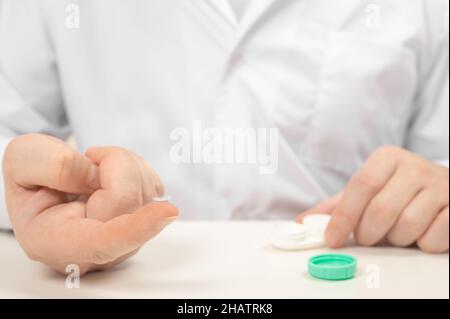 Contact lenses. Holding contact lens on finger tip. Man hand holding lens on finger. Customer, Ophthalmologist or eye doctor, oculist in clinic. Myopi Stock Photo