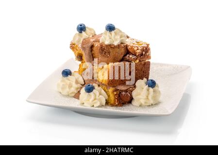 Panettone cake islices with Dulce de leche cream, blueberries and almonds. Italian dessert for Christmas in white dish on white background Stock Photo