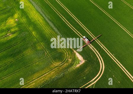 top down view of the tractor spraying the chemicals on the large green field Stock Photo