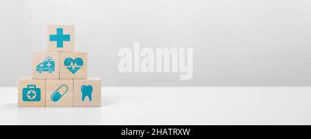 Medical symbols on wooden blocks stacked in a pyramid on white table. Healthcare and Insurance concept. stacking healthcare medicine and hospital icon Stock Photo