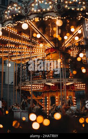 Shiny golden children's magic carousel with horses Merry-go-roundi n the evening lights. Vertical Stock Photo