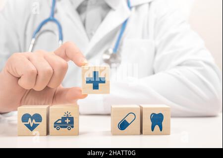 Doctor hand choose cross sign on wood cube block. healthcare medical icon on wooden blocks. doctor in white coat arranging cubes with medical symbols