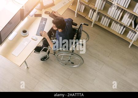 Top view handicapped and disability business man sitting on wheelchair working and checking on financial graph and stock market on monitor normally, e Stock Photo