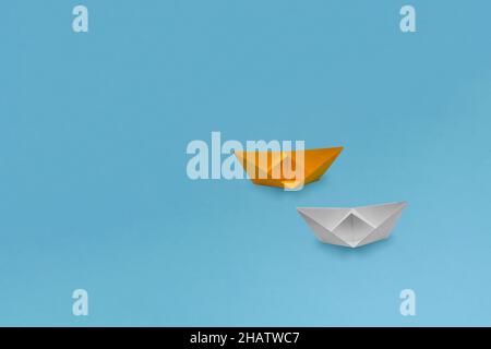 One yellow and one white paper ships (boats) of grainy paper on a blue background Stock Photo