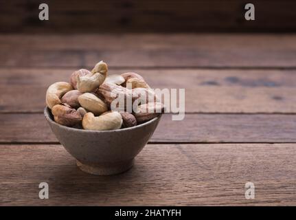 Cashews nuts with shells,homemade roasted process in ceramic bowl on wooden background Stock Photo