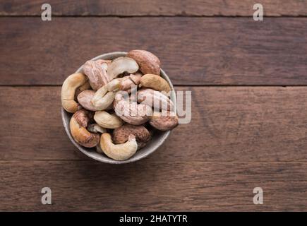 Cashews nuts with shells,homemade roasted process in ceramic bowl on wooden background Stock Photo