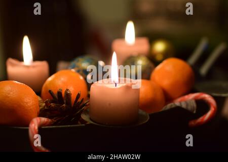 Three burning candles with manadarins and a pine cone as christmas decoration Stock Photo