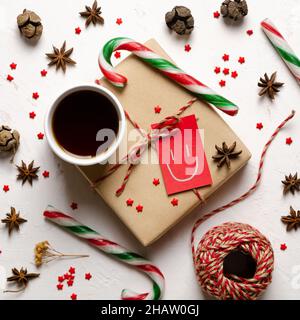 A cup of tea, some Christmas candy canes, little red stars, starred anise, pine cones, and a red and beige thread ball. Stock Photo