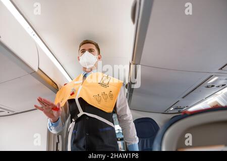 Flight attendant demonstrating how to use life vest in aircraft Stock Photo