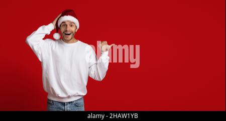 Look There. Excited Guy In Santa Hat Pointing Aside With Thumb Up Stock Photo