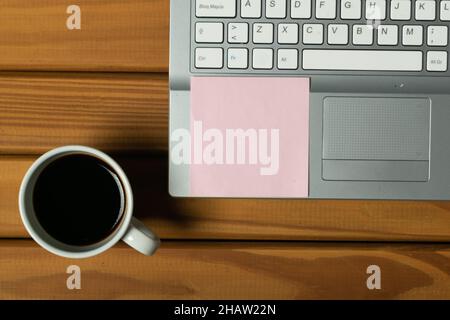 Aerial view of silver laptop with writing paper and coffee cup on wooden base Stock Photo