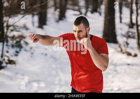 Muscular sportsman sparring in snowy forest at winter. Boxing in nature, winter sport, nature fitness Stock Photo