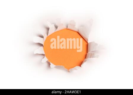 A hole in a white paper on an orange background, copy space. Stock Photo