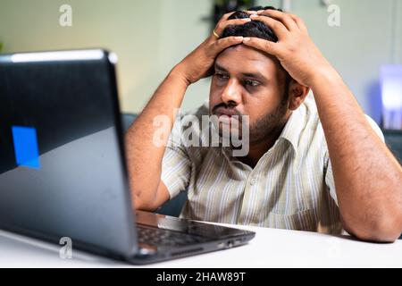 Sad fat man by reading mail about bad news from laptop during work from home - concept of interview rejection ,Missed promotion, evection notice and Stock Photo