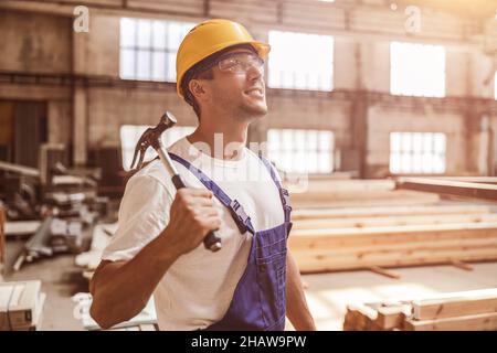 Cheerful builder with hammer working at construction site Stock Photo