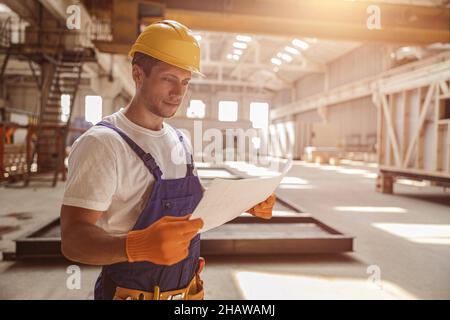 Male builder studying architectural plan at construction site Stock Photo