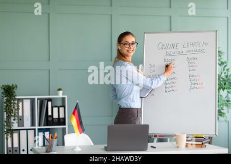 Cheerful teacher conducting online German lesson, talking to laptop webcam, explaining grammar rules to students Stock Photo