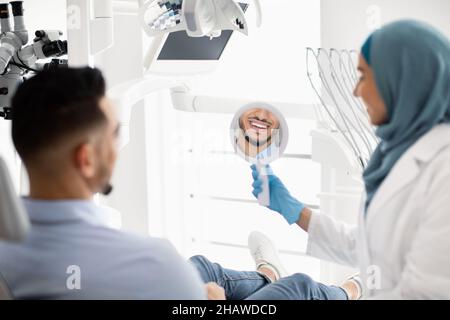 Arab Male Patient Looking At His Smile After Treatment In Dental Clinic Stock Photo