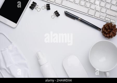 Work from home concept due to Covid-19 or Coronavirus with laptop,antibacterial hand gel, medical mask,coffee cup,pen,pine cone and mouse on white bac Stock Photo