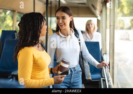 Cheerful multiethnic smiling women standing in bus and talking Stock Photo