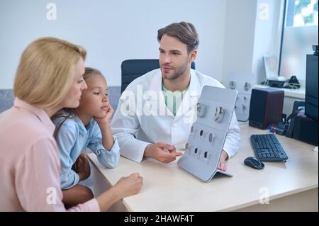 Man showing hearing aids to agirl and woman Stock Photo