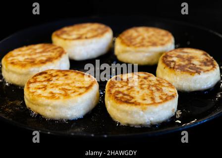 Cottage cheesecakes are fried in a frying pan. The process of cooking delicious homemade food. cheese pancakes or syrniki. Stock Photo