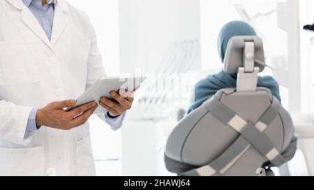 Technology And Healthcare. Dentist With Digital Tablet In Hands Standing In Cabinet Stock Photo