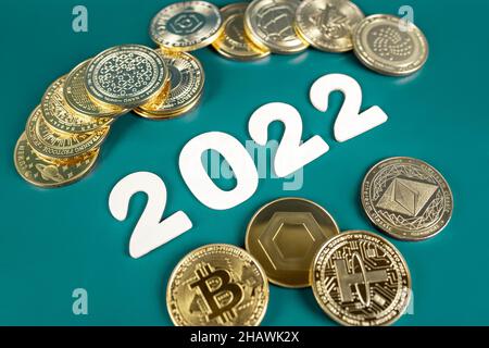 Cryptocurrency in 2022 price value prediction, forecast concept. Golden crypto coins Bitcoin, Ethereum, Tether, Nano, Chainlink and other next to the year numbers on green background. Stock Photo