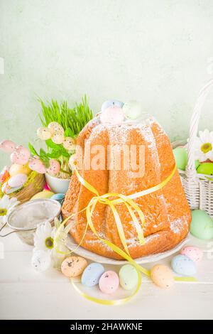 Easter sweets and decorations background, Sweet easter cake panettone with colorful painted eggs, spring grass and decor, copy space for text Stock Photo