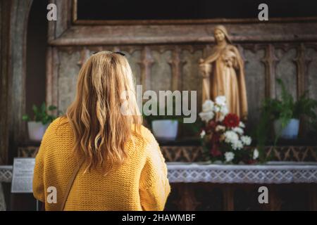 Woman praying to Virgin Mary in church. Faith and hope concept. Catholicism and christianity in European culture Stock Photo