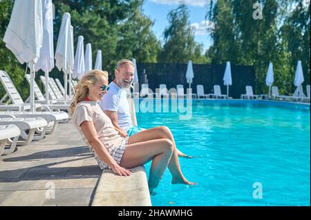 Mature couple enjoying good weather near the swimming pool Stock Photo