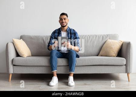 Portrait of smiling Arab man using tablet at home Stock Photo
