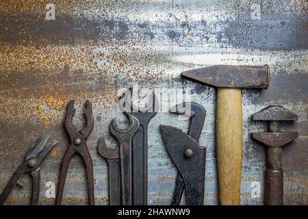 Plumber tools on rusty metal table, flat lay. Hammer, wrench, pliers, adjustable wrench and other industrial tool. Retro style Stock Photo