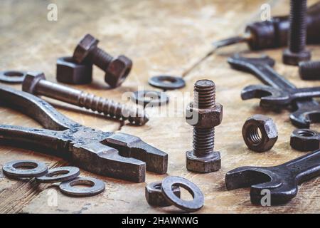 Old rusty metal screw and work tools on table in workshop. Household equipment. Wrench, pliers, bolt, washer and nut fastener Stock Photo