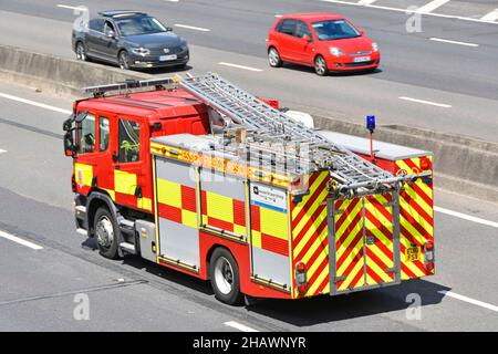 Aerial side back view Essex Fire & Rescue Service fire brigade engine blue light emergency shout driving on UK motorway beside concrete crash barrier Stock Photo