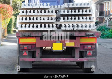 Back & end street view of articulated trailer delivery to house building construction site of a load of precast concrete floor plank beams England UK Stock Photo