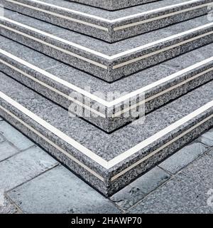 Close up view of corner flight of speckled stone steps at entrance to elevated public walkway leading to office building entrance London England UK Stock Photo