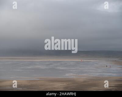 Sea mist, fog, coming in over Westward Ho in Devon, England. Unrecognisable people on beach. Stock Photo